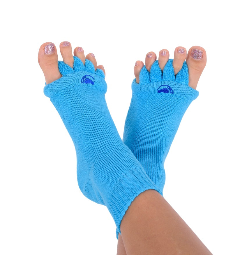 Zwei Füße in leuchtend blauen Fußausrichtungssocken mit offenen Zehen und glitzernd lackierten Nägeln. Die Socken sind mit aufgestickten blauen Halbmonden in Zehennähe versehen und vereinen Stil und Komfort.