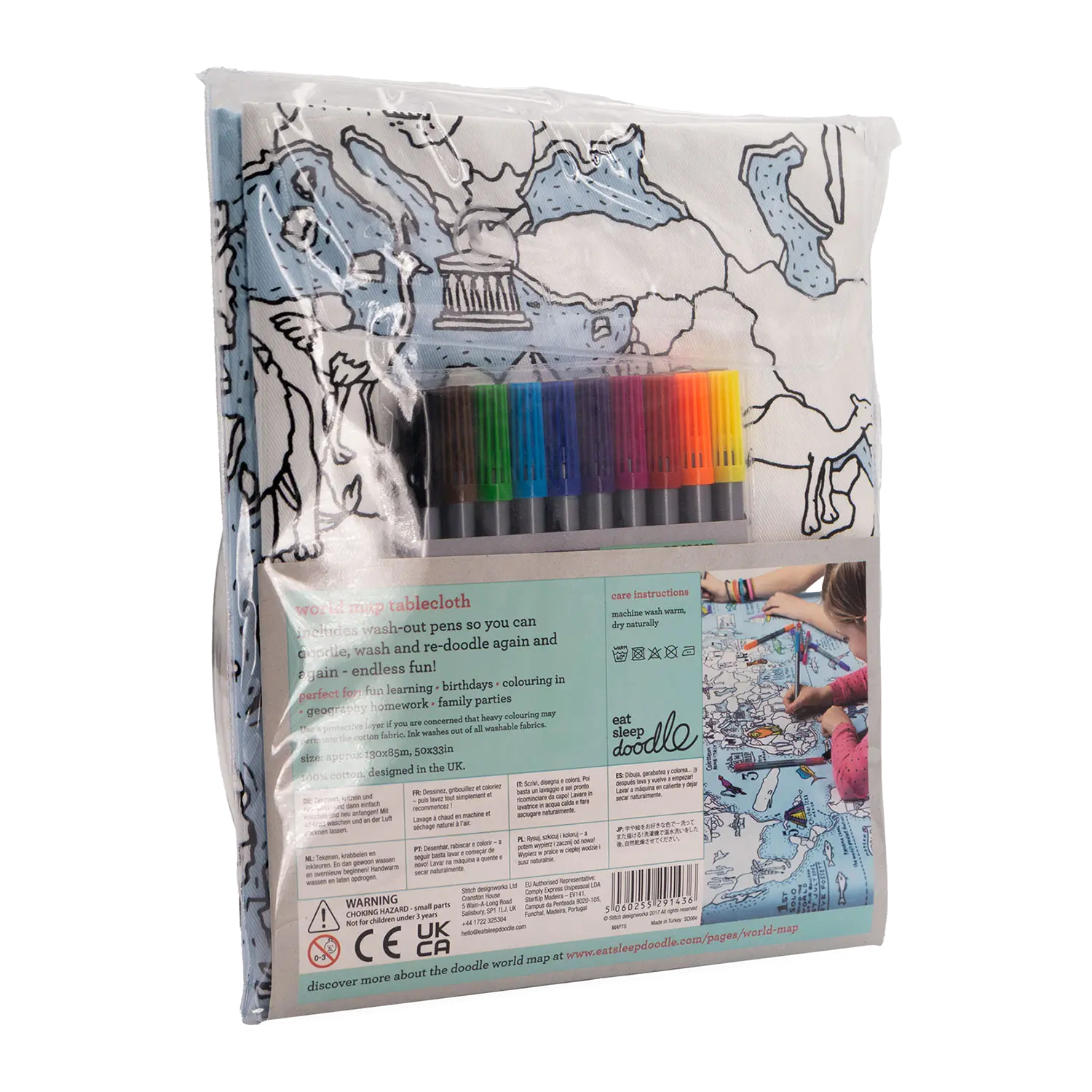 Die Baumwolltischdecke „Color In World Map“ wird mit bunten, abwaschbaren Stoffmarkern geliefert. Die Verpackung zeigt ein Kartenmotiv und ein Foto einer Person, die gerade malt. Auf der Rückseite befinden sich Sicherheitshinweise und Gebrauchsanweisungen.
