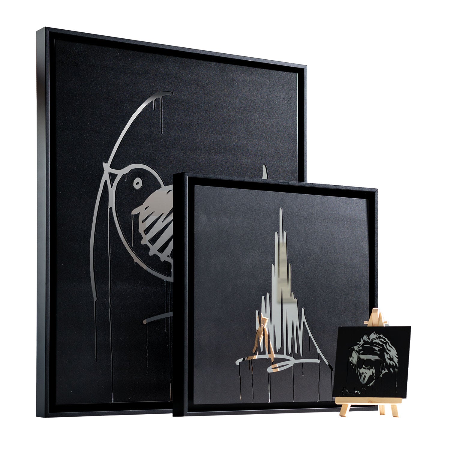 Der Ulmer Schachtel Designspiegel Staffelei präsentiert drei minimalistische, von Graffiti inspirierte schwarze Gemälde mit einem Vogel, einer abstrakten vertikalen Form und einem Löwengesicht. Jedes Gemälde ist in einem eleganten schwarzen Rahmen vor tiefschwarzem Hintergrund gehalten.