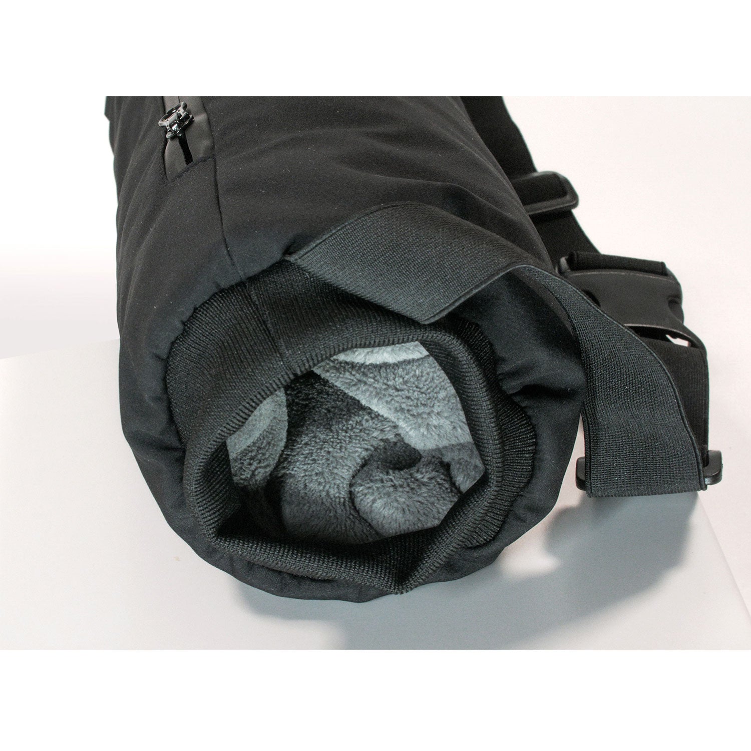 Eine schwarze, zylindrische Kameraobjektivtasche „Handwärmer Muff“ ist teilweise geöffnet und gibt den Blick auf ein graues, flauschiges Innenfutter frei, das auf mobile Wärme hindeutet. Der gepolsterte Schultergurt sorgt für Komfort bei Outdoor-Aktivitäten und ist auf schlichtem, weißem Hintergrund abgebildet.