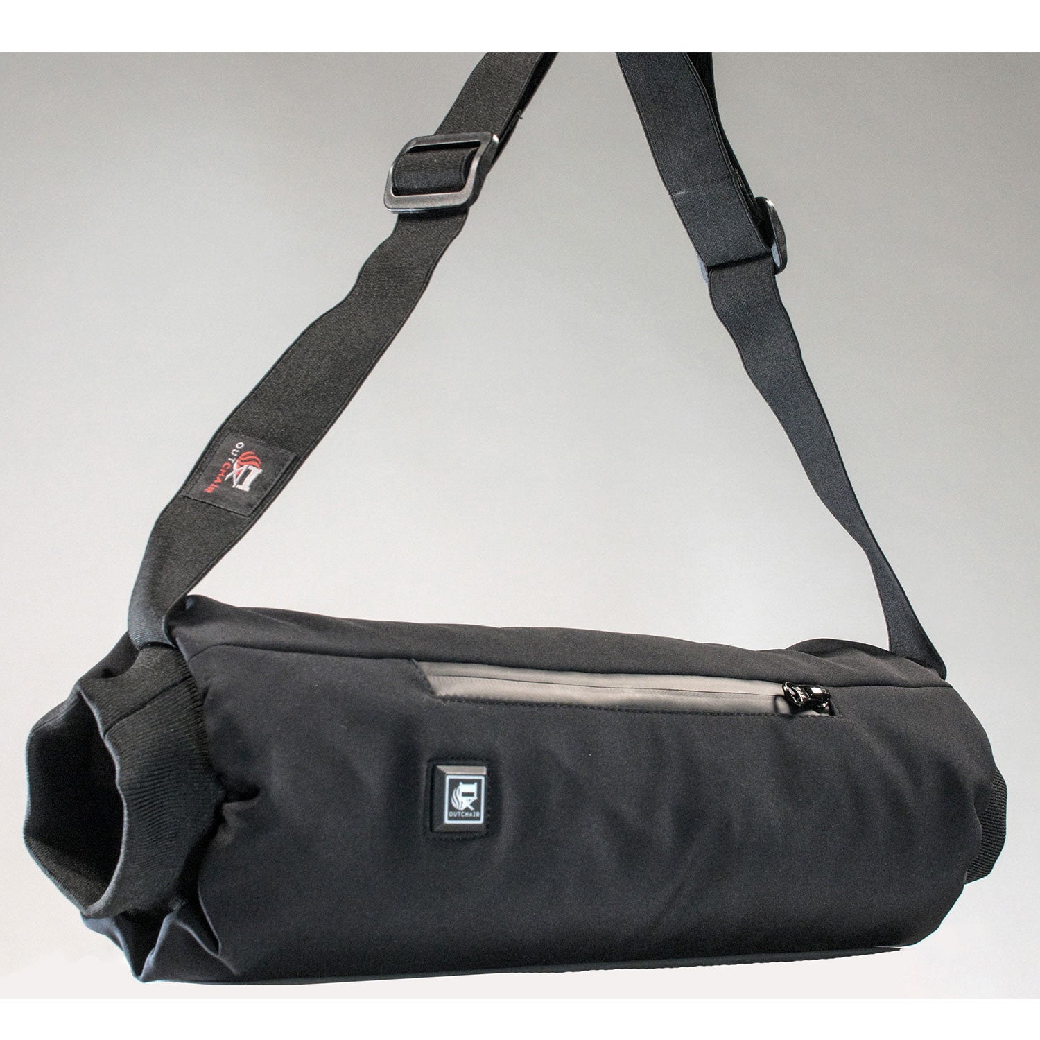 Der Handwärmer Muff ist eine schwarze, zylindrische Umhängetasche, ideal für Outdoor-Aktivitäten. Er verfügt über einen verstellbaren Riemen, eine Reißverschlusstasche vorne und ein dezentes Logo auf schlichtem grauem Hintergrund.