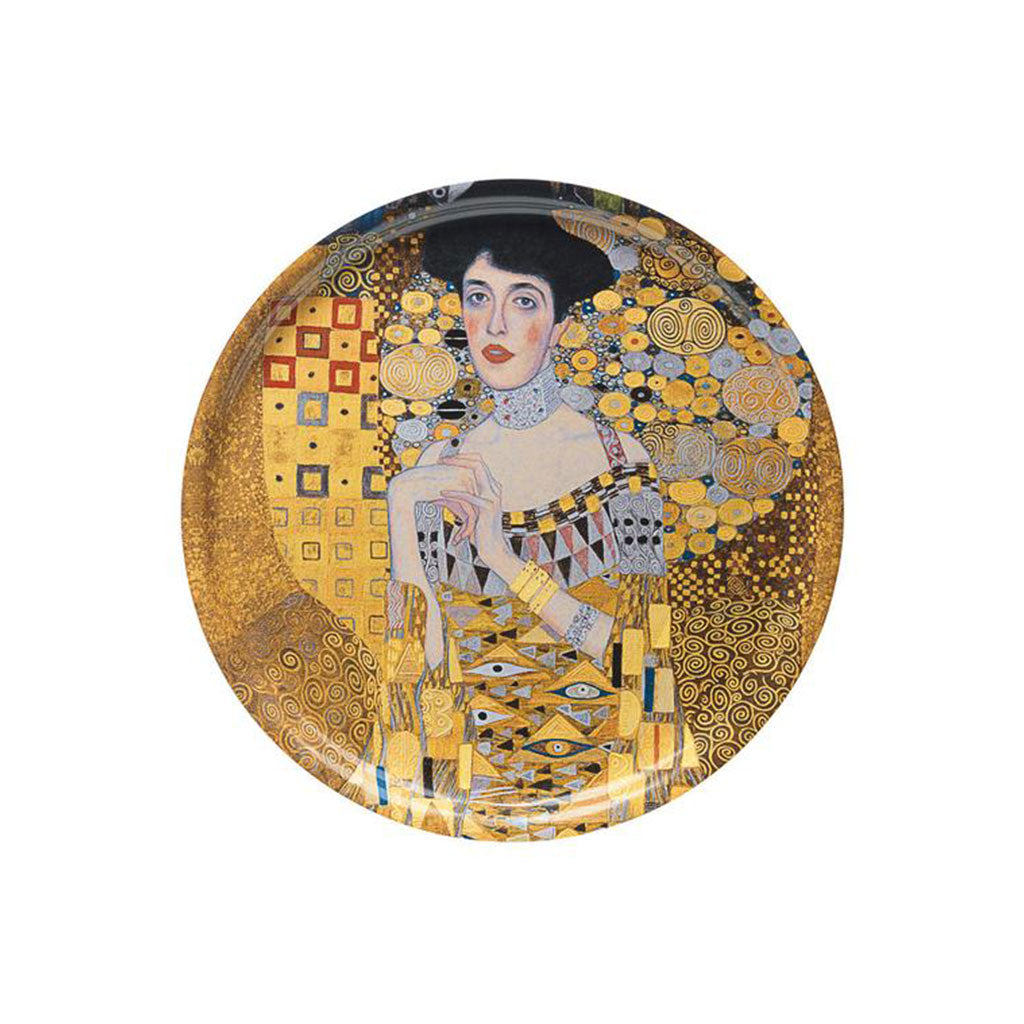Der runde Dekoteller der ars mundi Exklusiv-Edition mit dem Namen „Holztablett ‚Adele Bloch-Bauer‘“ zeigt eine Reproduktion von Gustav Klimts Gemälde einer Frau mit kurzen dunklen Haaren in gemustertem Kleid und Hut vor dem Hintergrund seiner Goldenen Periode mit wirbelnden goldenen Mosaikmustern.