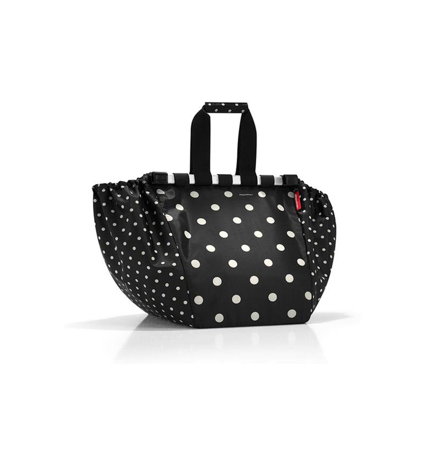 Die Reisenthel Easyshoppingbag dots ist eine schwarze Handtasche mit weißen Punkten und einer schmalen Öffnung. Sie hat schwarze Griffe mit roten Akzenten und einen rechteckigen Boden vor einem schlichten weißen Hintergrund. Sie ist eine umweltfreundliche Wahl für alle, die Wert auf Stil und Nachhaltigkeit legen.
