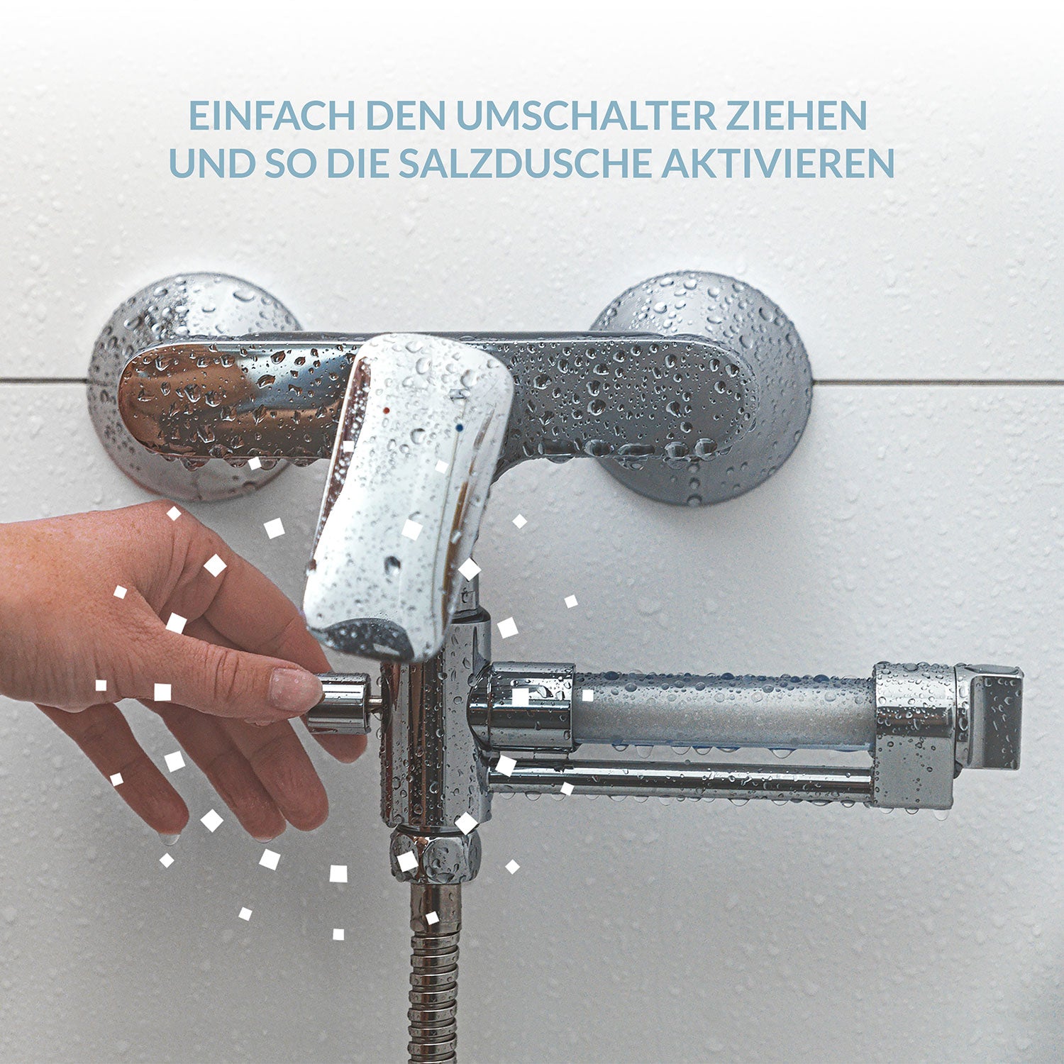 Eine Hand greift nach einem Duschumsteller unter einem nassen Wandhahn. Der obige Text lautet: „Einfach den Umschalter ziehen und so die ‚Deine Salzdusche für Zuhause‘ aktivieren“ und betont die Vorteile für empfindliche Haut.