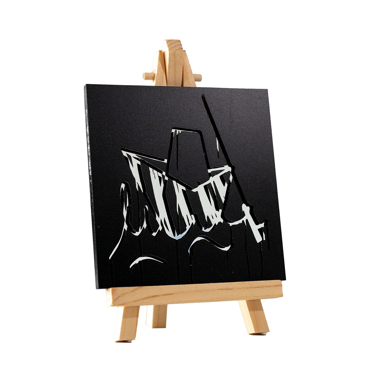 Der Ulmer Schachtel Designspiegel Staffelei zeigt abstrakte Schwarz-Weiß-Kunstwerke mit Graffiti-inspirierten, kräftigen, eckigen Pinselstrichen, die dynamische Formen auf einem tiefschwarzen Hintergrund erzeugen und so eine urbane Note und kreatives Flair einfangen.