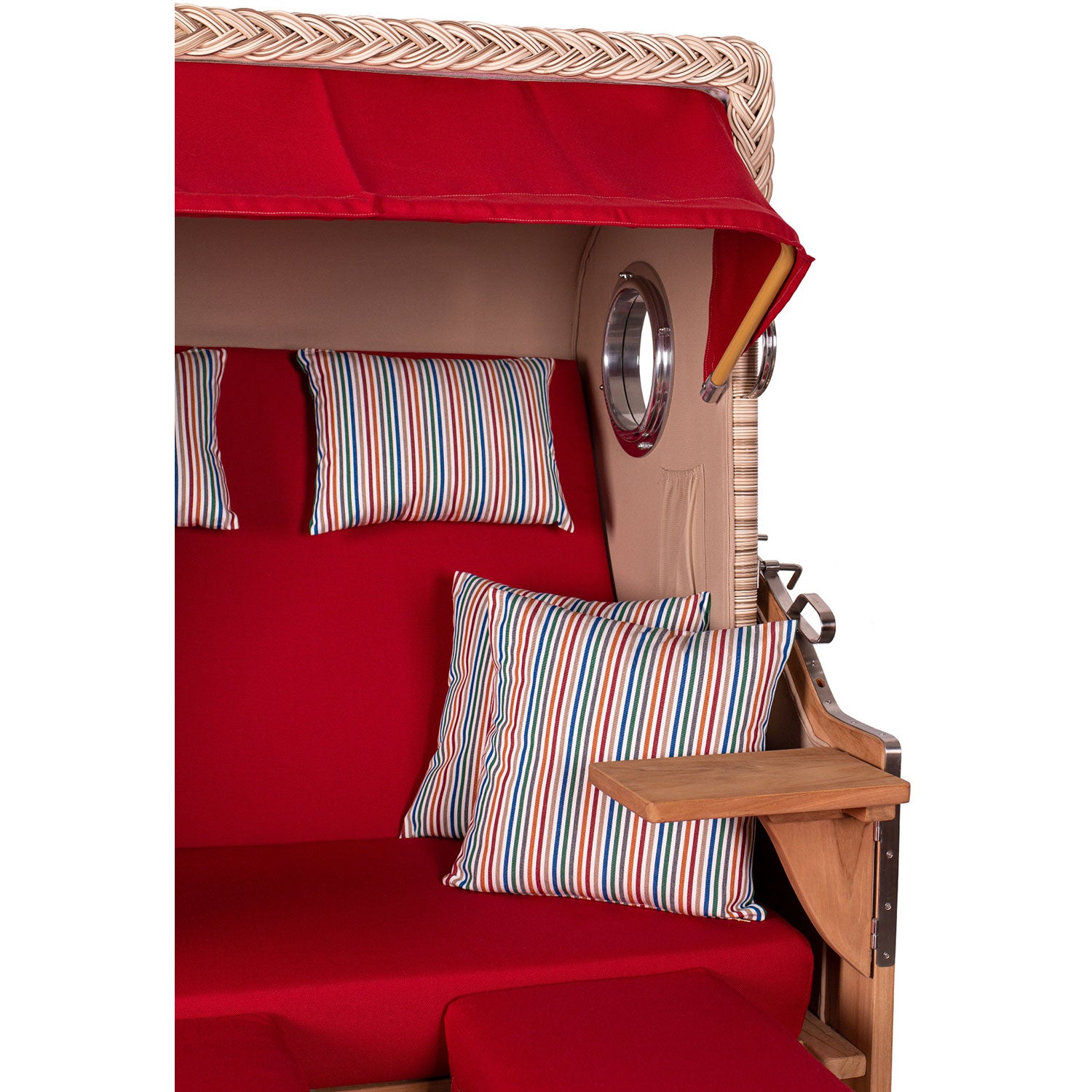 Der Strandkorb DÜNE mit roten Kissen und gestreiften Polstern verfügt über hölzerne Seitenablagen, ein Dach, ein gewebtes Muster auf der Oberseite, runde Fenster an der Seite und ist aus strapazierfähigem Teakholz gefertigt, um dauerhafte Eleganz am Meer zu gewährleisten.