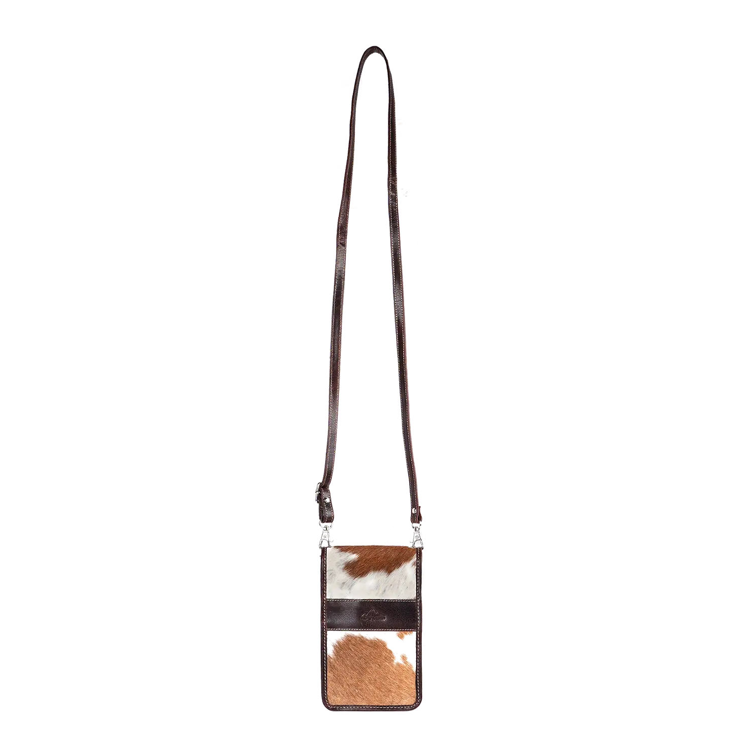 Die Umhängetasche SPRUCHBEITEL ist eine kleine rechteckige Umhängetasche aus Rindsleder mit langem Riemen und einem Patchwork aus braunem und weißem Fell, das einen natürlichen, rustikalen Charme verleiht.