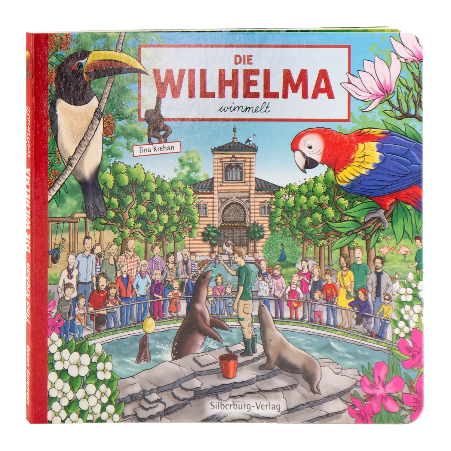 „Die Wilhelma wimmelt“, ein illustriertes Kinderbuch von Tina Krehan, zeigt eine lebendige Zooszene im zoologisch-botanischen Garten Stuttgart mit Tieren wie Tukanen und Papageien inmitten von Robben, Blumen und Menschenmengen. Erschienen im Silberburg-Verlag.