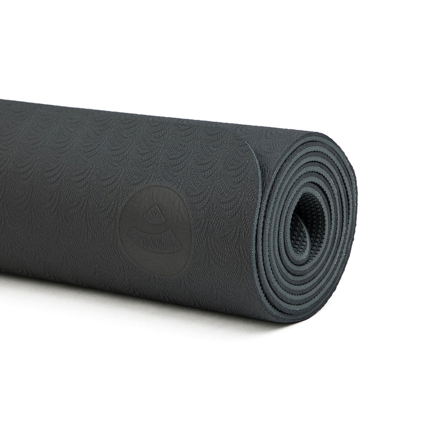 Die gerollte schwarze Yogamatte LOTUS PRO besticht durch ein dezentes Prägemuster mit einem kleinen, runden Logo. Sie besteht aus TPE und wirkt dick und strukturiert. Das deutet darauf hin, dass sie für Komfort und Griffigkeit beim Training konzipiert und gleichzeitig umweltfreundlich ist.