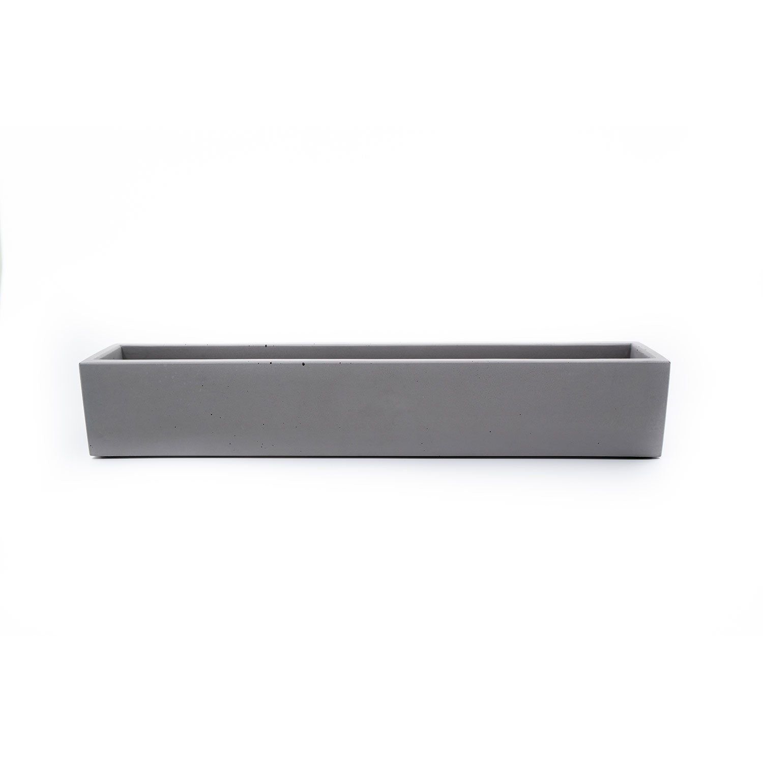 Der Beton Blumenkasten grau, länglich ist ein minimalistischer, langer Blumenkasten aus grauem Beton, der vor einem schlichten weißen Hintergrund Eleganz verleiht.