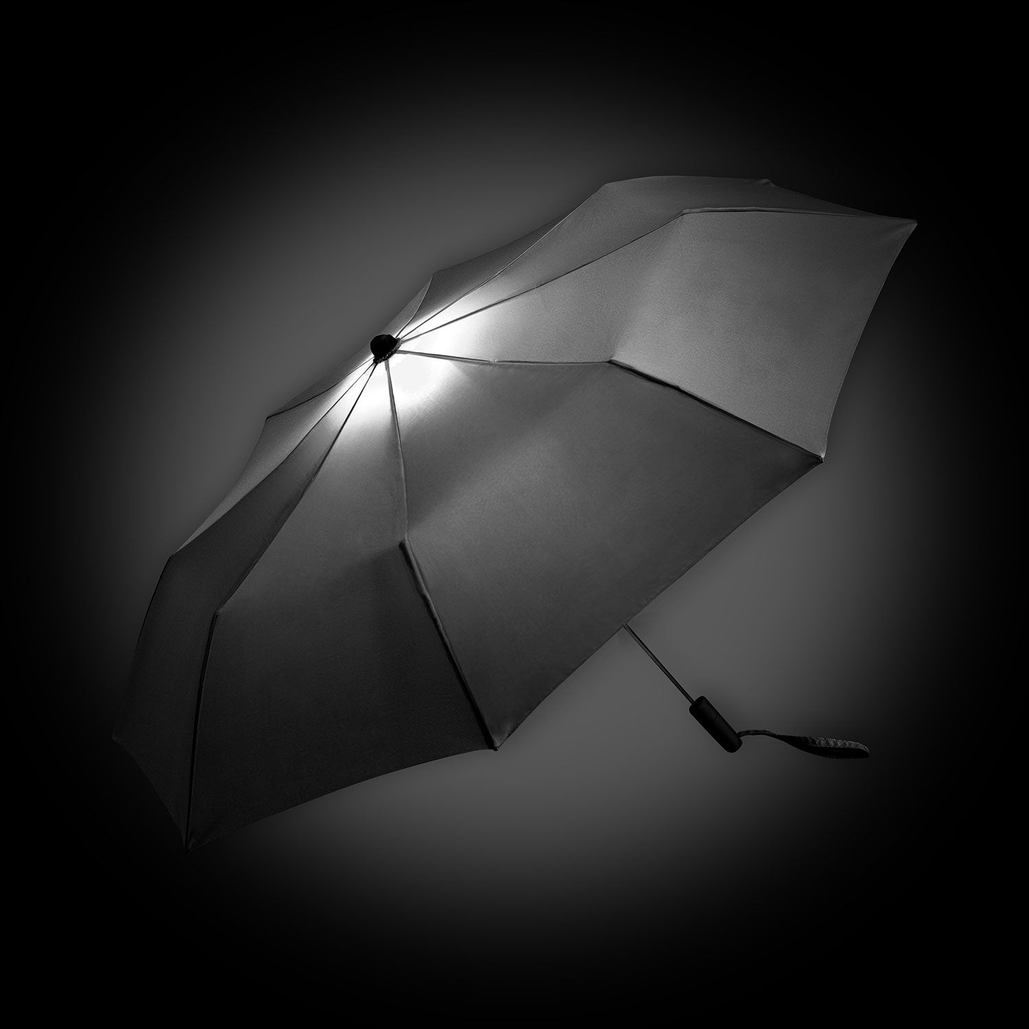 Der Oversize-Taschenschirm mit Beleuchtung ist ein schwarzer Regenschirm mit integrierter LED-Beleuchtung für einen Halo-Effekt. Mit acht Panelen und einem Windproof-System kombiniert er robustes Design mit leuchtendem Charme vor dunklen Hintergründen.